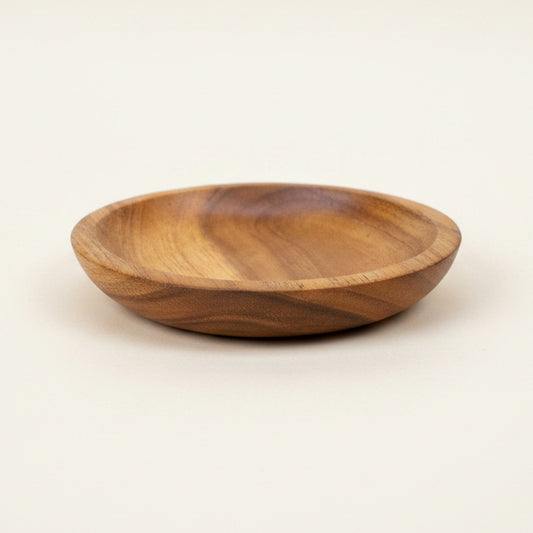A small round wooden dish with a warm honey-brown finish and visible wood grain