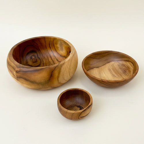 Three handcrafted wooden bowls of varying sizes with rich natural grain patterns