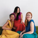 Three women sitting on a green couch against a white background