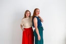 Two women standing back-to-back against a white background, wearing colorful outfits.