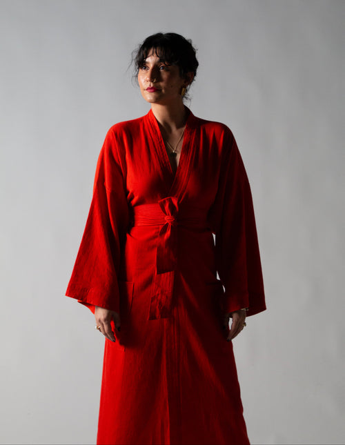 Person wearing a red robe against a plain background
