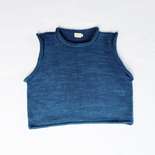 A sleeveless blue ribbed knit crop top laid flat on a white sheet, with a small white neck label visible.
