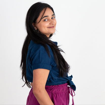 Woman wearing a blue shirt and purple pants on a white background