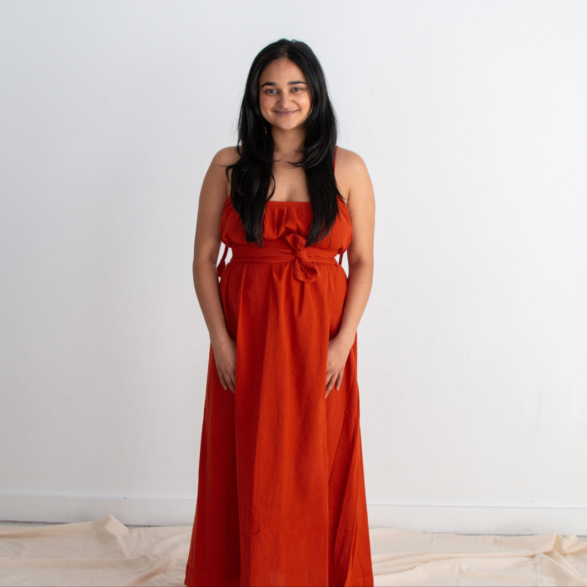 Woman wearing a red dress standing against a white background