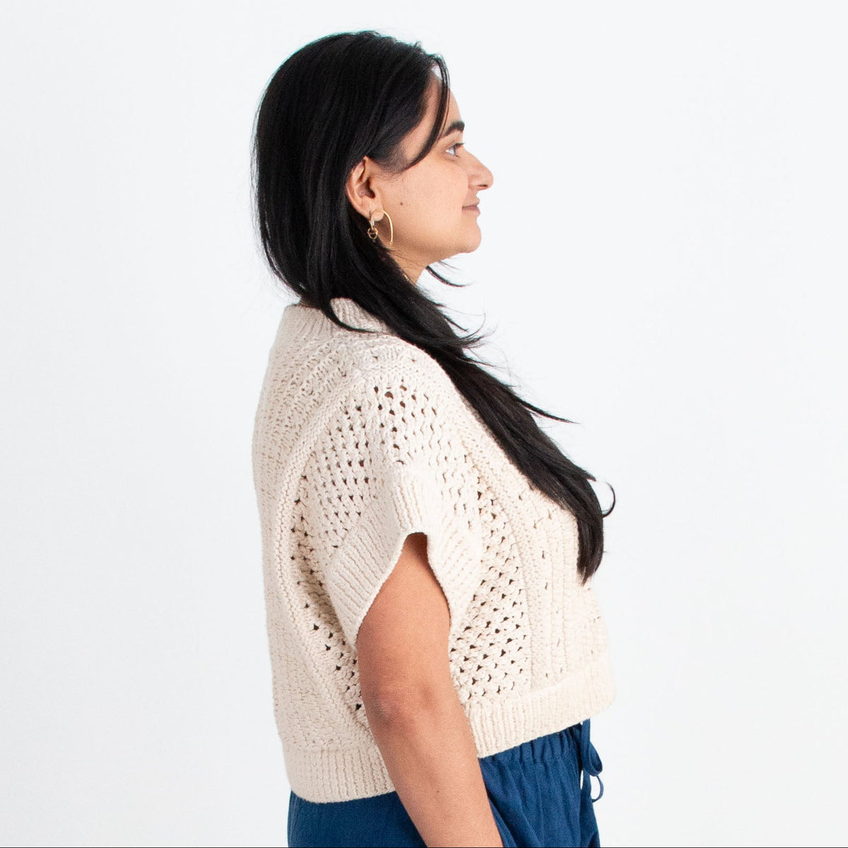 Woman wearing a white top and blue pants standing on a white background