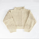 A cream-colored open-knit mock-neck sweater laid flat 