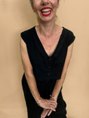 Woman wearing a black top and wide leg trousers with a beige background