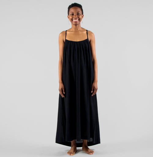 Woman wearing a black dress standing on a white background in a studio setting