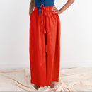Woman wearing a blue top and red pants standing on a white background