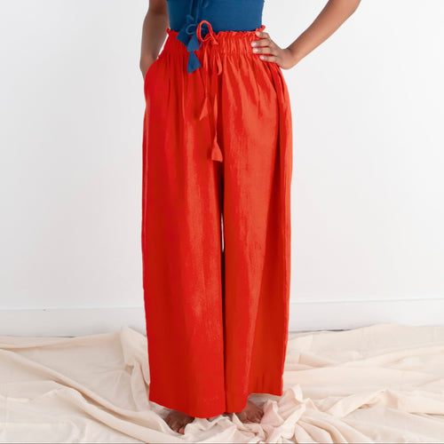 Woman wearing a blue top and red pants standing on a white background