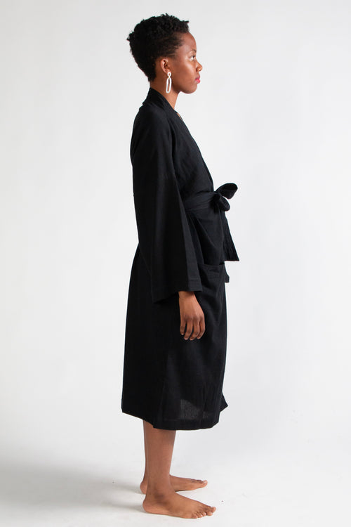 Person wearing a black robe standing against a white background