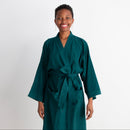 Woman wearing a teal robe against a white background