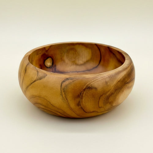 A handcrafted wooden bowl with a rich golden-brown and amber wood grain pattern