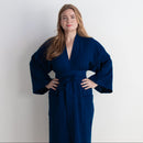 Woman wearing a blue wrap dress against a white background