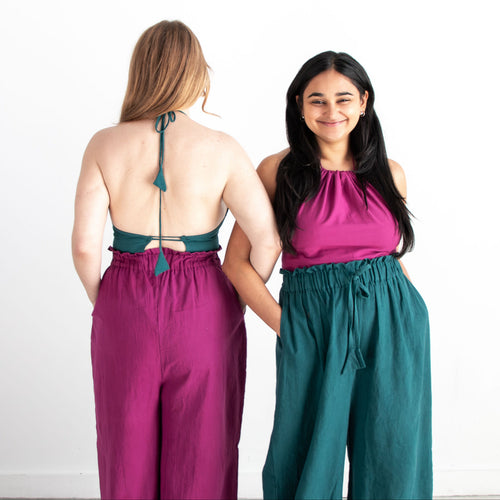 Two women wearing matching outfits with one facing away and the other facing forward on a white background.