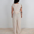 Person wearing a beige outfit standing against a white background