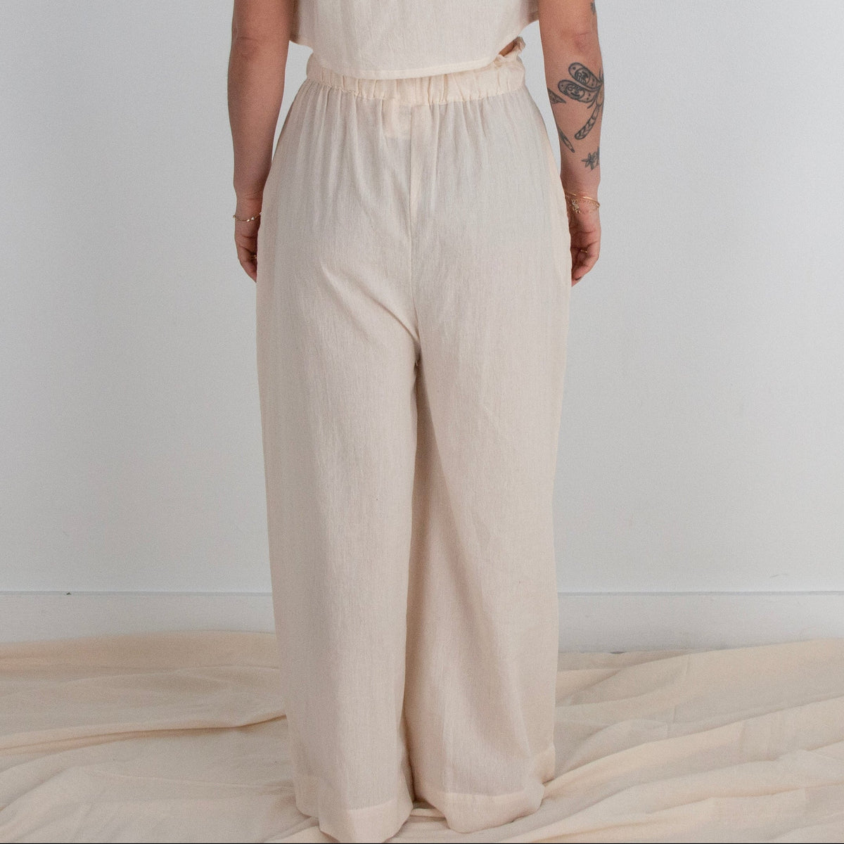Person wearing a beige outfit standing against a white background