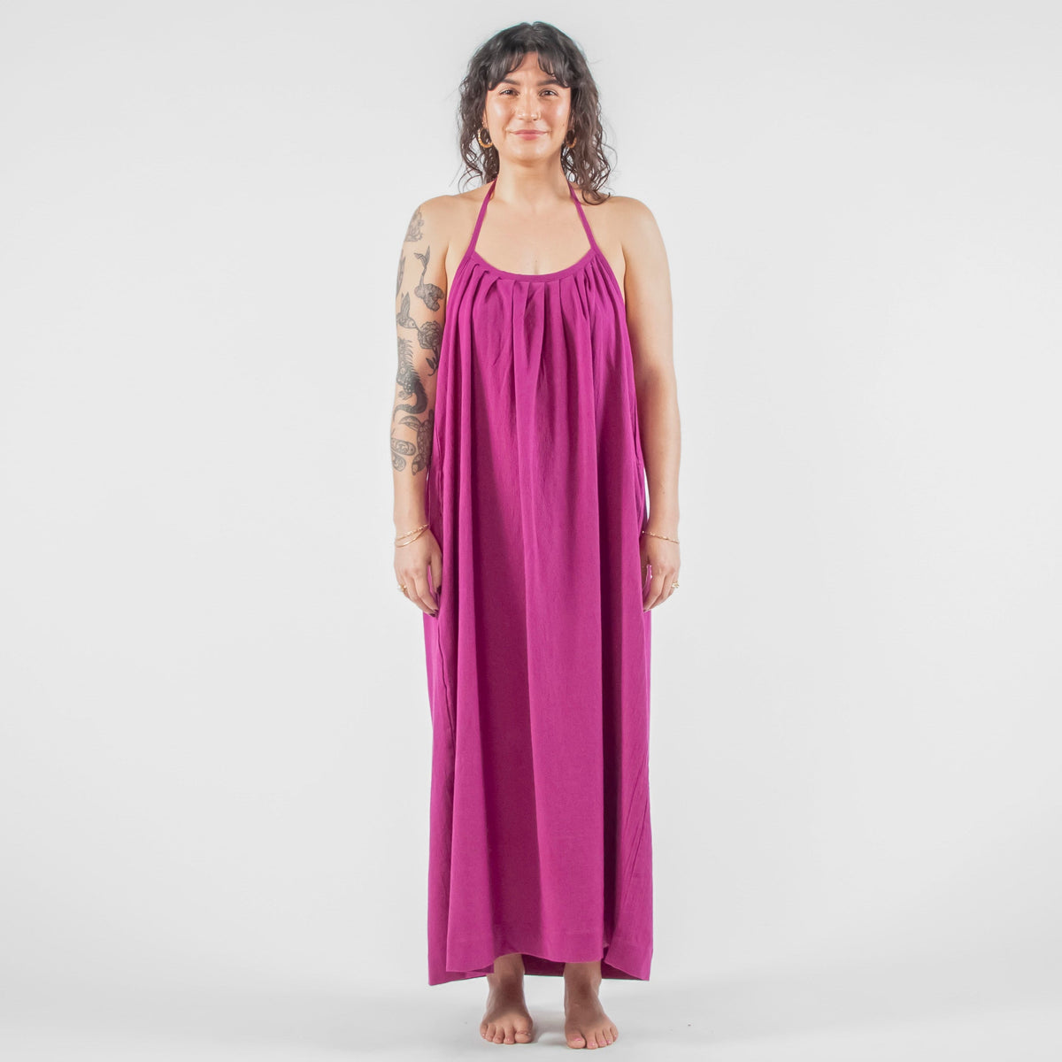 Woman wearing a purple dress standing on a white background in a studio setting.