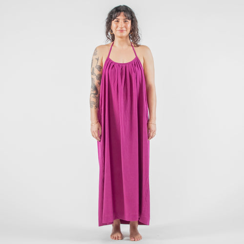 Woman wearing a purple dress standing on a white background in a studio setting.
