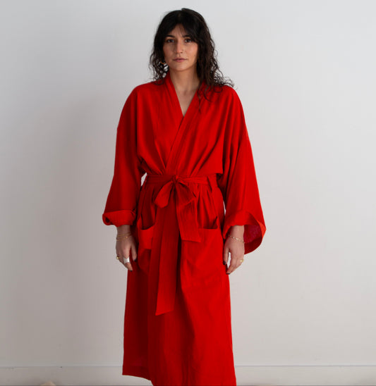 Woman wearing a red robe against a plain background
