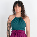 Woman wearing a teal top and magenta skirt against a white background