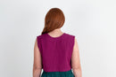 Person wearing a purple sleeveless top with a plain background