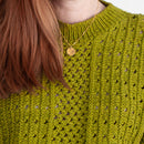 Woman wearing a green knitted top and teal skirt against a white background