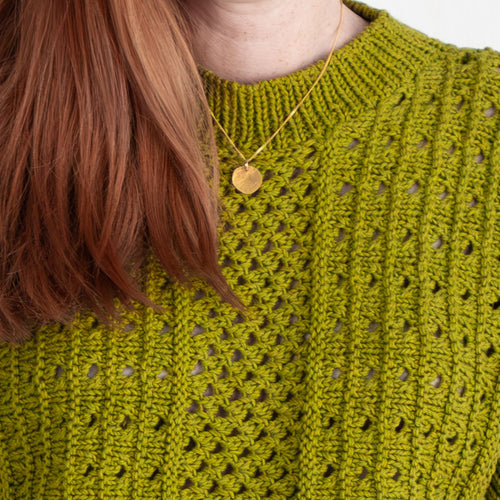 Woman wearing a green knitted top and teal skirt against a white background