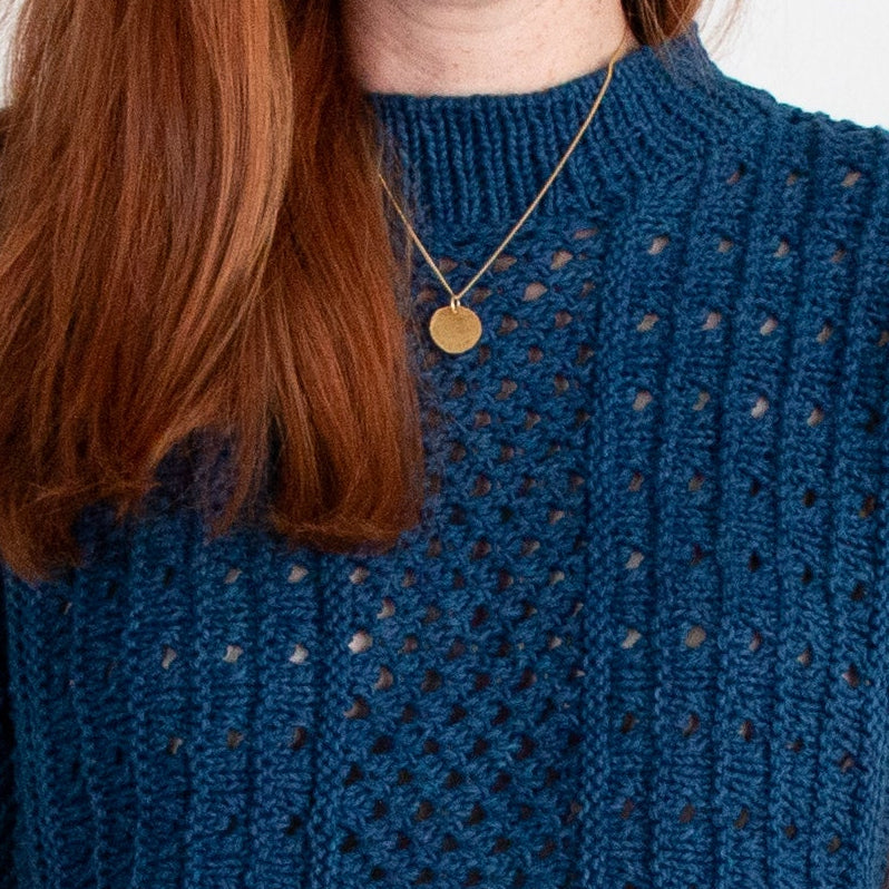 woman with red hair wearing a textured indigo knit sweater
