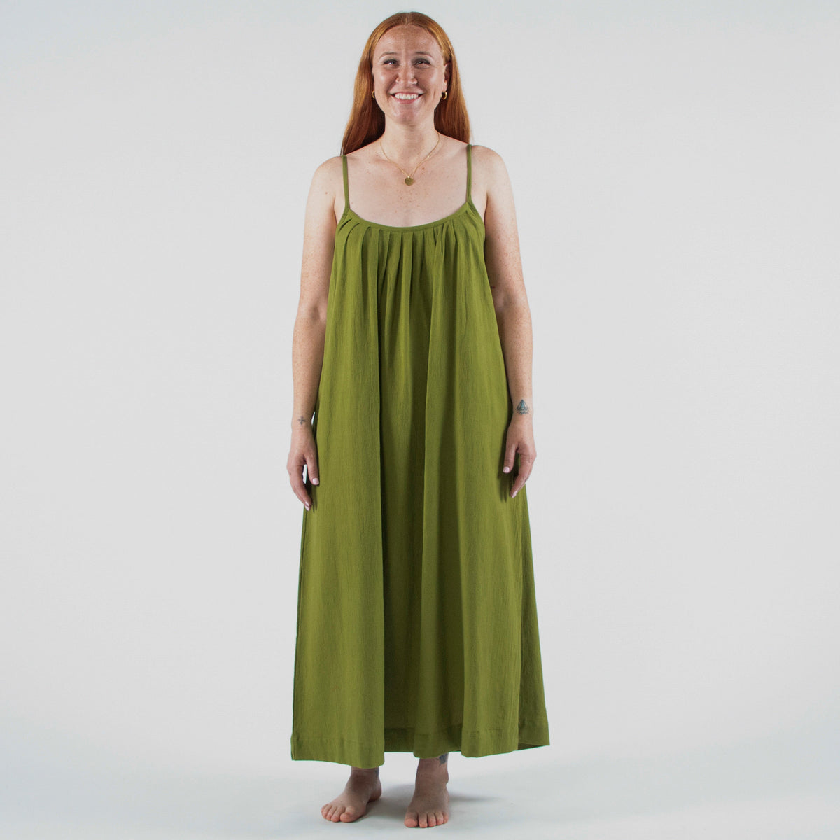 Woman wearing a green dress standing in a photo studio with equipment around.