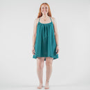 Woman wearing a teal dress standing on a white background in a photo studio.