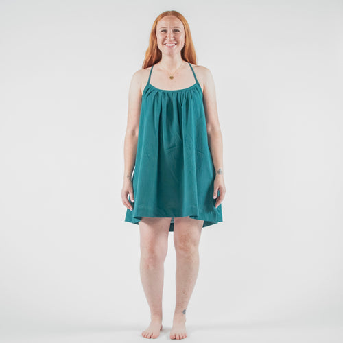 Woman wearing a teal dress standing on a white background in a photo studio.