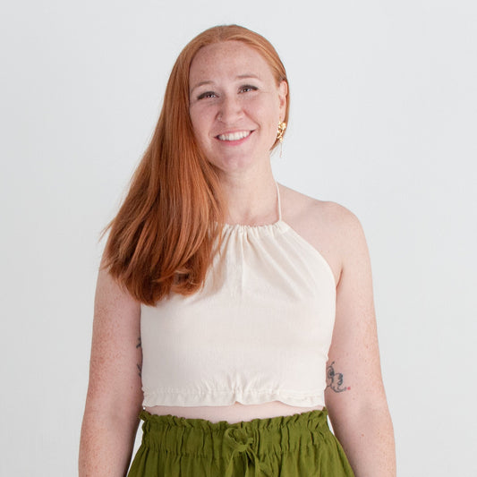 Woman wearing a white top and green pants against a white background