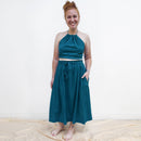 Woman wearing a teal dress standing on a white background
