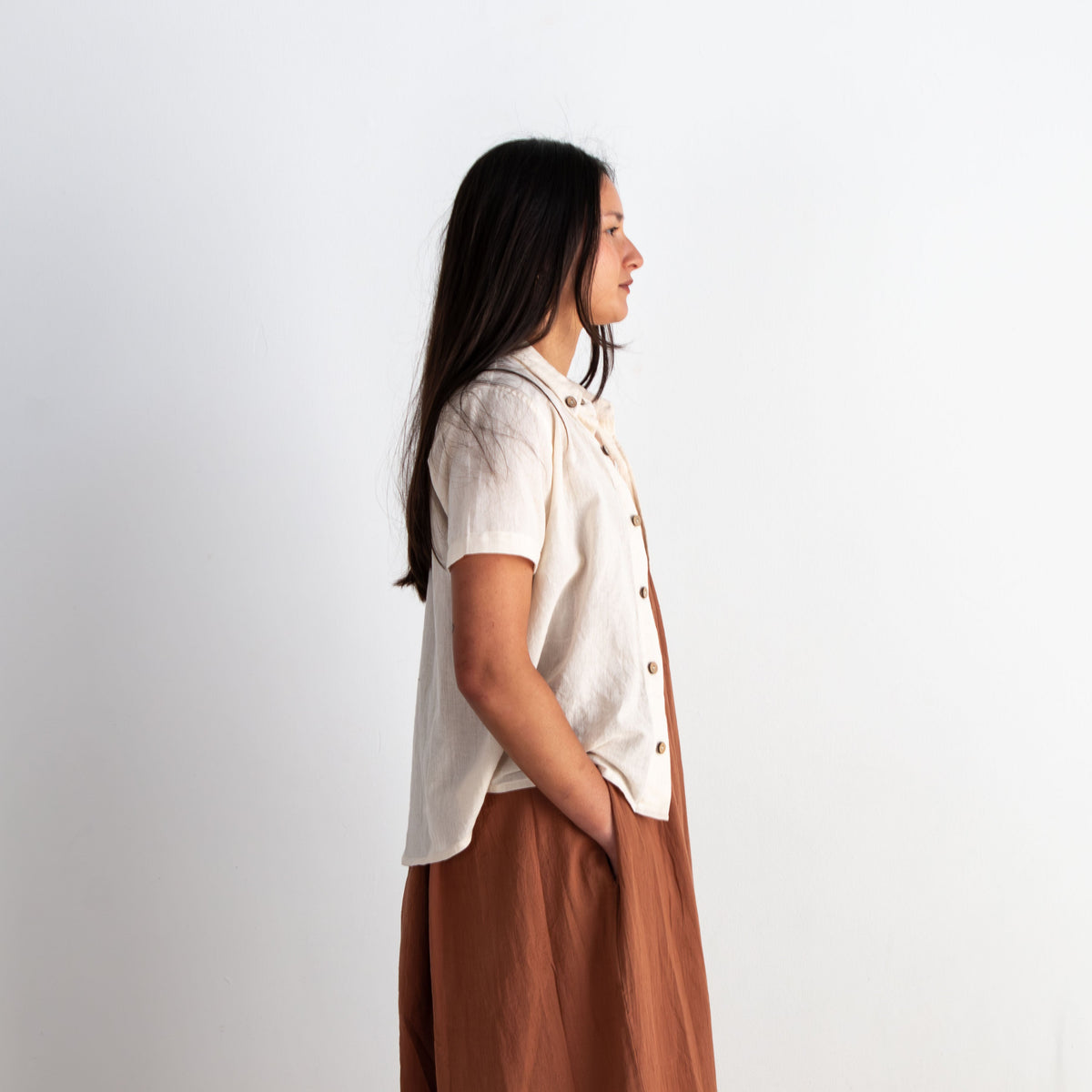 Woman standing in profile against a plain white background