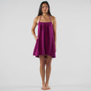 Woman wearing a purple dress standing in a studio setting with white backdrop