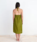Woman wearing a green dress standing on a white floor with a white wall background