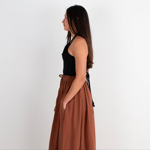 Woman wearing a black top and brown skirt on a white background