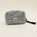 A quilted, striped cosmetic pouch with a black wrist strap