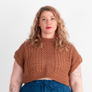 Woman wearing a brown knitted top and blue pants on a white background