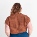 Person wearing a brown knitted sweater and blue pants on a white background